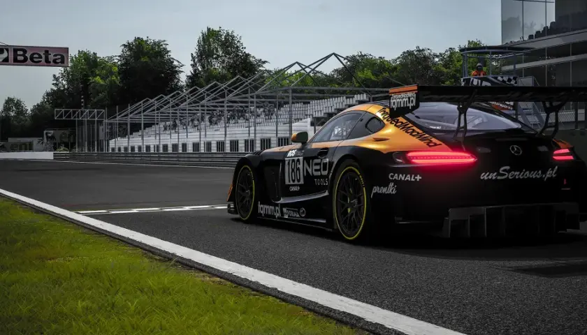 Czarny samochód wyścigowy z pomarańczowymi akcentami na torze. Widoczne logo "unSerious.pl", sugerujące polskie spolszczenie do Assetto Corsa.