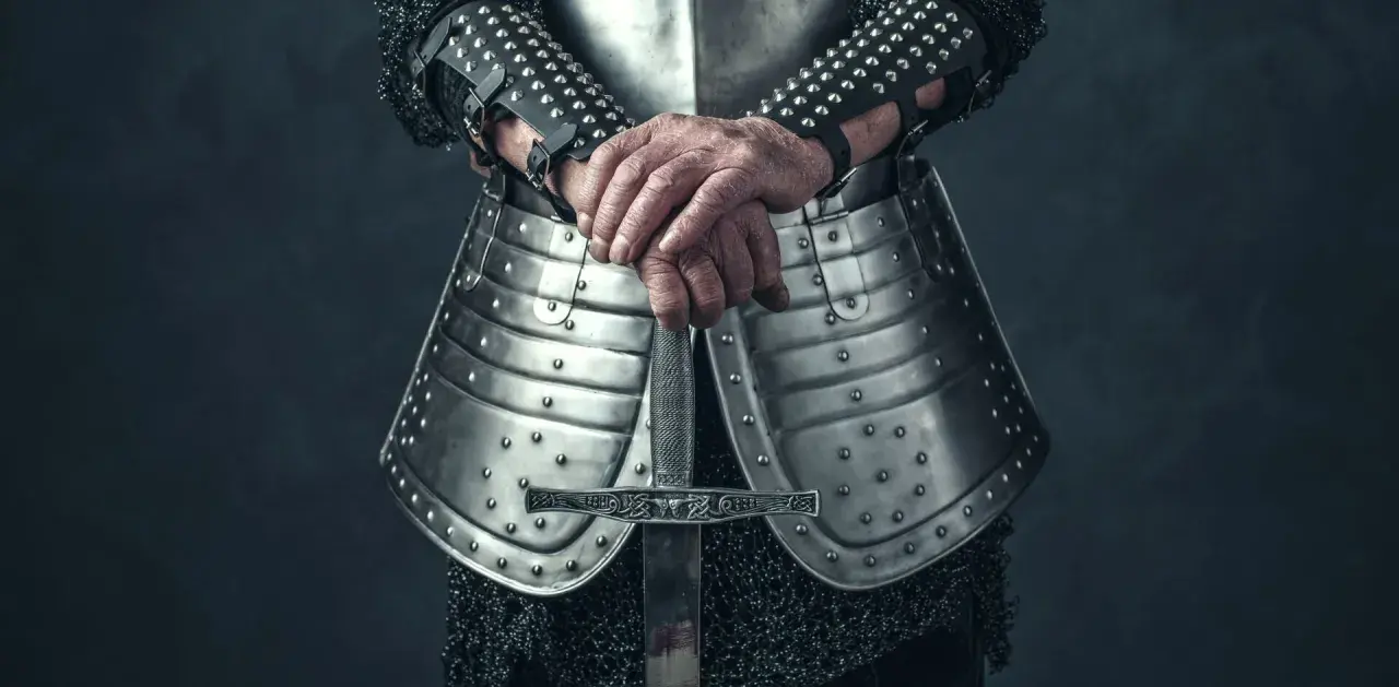 Rycerz w zbroi trzyma miecz. Może szukać bannerlord cheats, by zdobyć przewagę w bitwie.